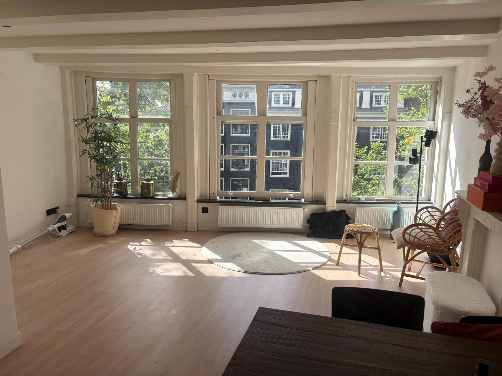 Bright living room with large windows overlooking Amsterdam canal houses